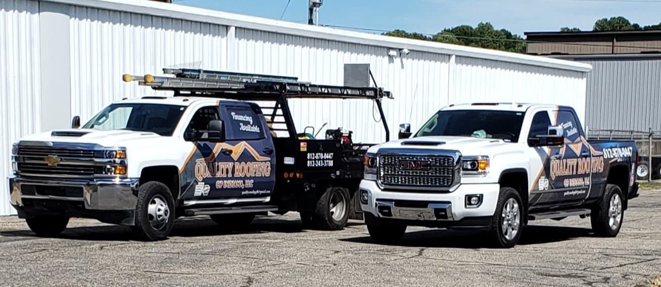 Two Quality Roofing trucks positioned in the company parking lot.